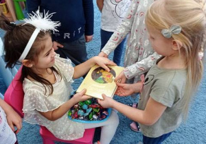 Dzieci wręczają prezent książkowy jubilatce.